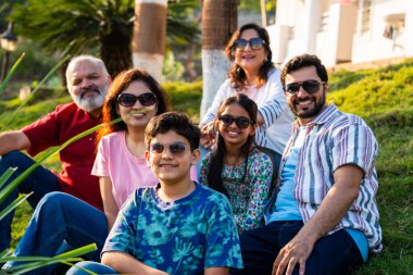 Hint ailesi çimlerin yamacında oturmuş mutlu anların tadını çıkarıyor ve gevşemiş sohbetler ediyorlar. Büyükbabalar, ebeveynler ve çocuklar doğada huzur içinde vakit geçiriyorlar. Birbirlerine bağlanıp gülümsüyorlar.