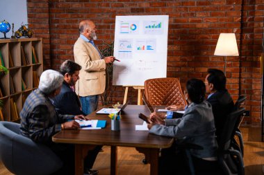 Hintli işadamları, Hindistan 'ın Asya iş dünyasının üst düzey yöneticileri olarak, şirket büyümesini ve finansal projeksiyon stratejisini modern ofiste incelerken, grafikte tartışıyorlar.