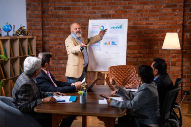 Hintli işadamları, Hindistan 'ın Asya iş dünyasının üst düzey yöneticileri olarak, şirket büyümesini ve finansal projeksiyon stratejisini modern ofiste incelerken, grafikte tartışıyorlar.