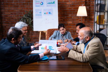 Hintli üst düzey iş adamları, Hindistan 'da üst düzey Asyalı iş adamları olarak birlikte çalışarak, rahat, modern kurumsal işyerlerindeki görevleri incelerken dizüstü bilgisayarları ve masa başındaki kağıtları kullanarak iş birliği yapıyorlar.