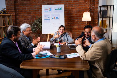 Hintli üst düzey iş adamları, Hindistan 'da üst düzey Asyalı iş adamları olarak birlikte çalışarak, rahat, modern kurumsal işyerlerindeki görevleri incelerken dizüstü bilgisayarları ve masa başındaki kağıtları kullanarak iş birliği yapıyorlar.