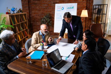 Hintli işadamları, Hindistan 'da rahat modern ofis masasında çalışırken, üst düzey Asyalı iş adamları ve üst düzey yönetim stratejisi olarak plan üzerinde tartışıyorlar.