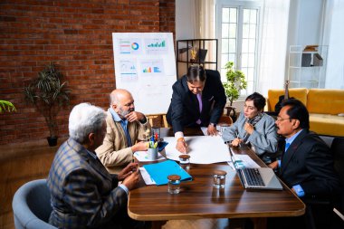 Hintli işadamları, Hindistan 'da rahat modern ofis masasında çalışırken, üst düzey Asyalı iş adamları ve üst düzey yönetim stratejisi olarak plan üzerinde tartışıyorlar.