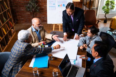 Hintli işadamları, Hindistan 'da rahat modern ofis masasında çalışırken, üst düzey Asyalı iş adamları ve üst düzey yönetim stratejisi olarak plan üzerinde tartışıyorlar.