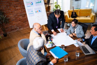 Hintli işadamları, Hindistan 'da rahat modern ofis masasında çalışırken, üst düzey Asyalı iş adamları ve üst düzey yönetim stratejisi olarak plan üzerinde tartışıyorlar.