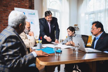Hintli işadamları, Hindistan 'da rahat modern ofis masasında çalışırken, üst düzey Asyalı iş adamları ve üst düzey yönetim stratejisi olarak plan üzerinde tartışıyorlar.
