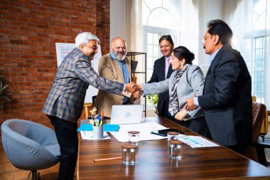 Hintli iş adamları anlaşmadan sonra el sıkışıyor. Hintli kıdemli Asyalı işadamı modern ofis toplantılarında gülümserken başarılı bir anlaşmayı imzalıyor.