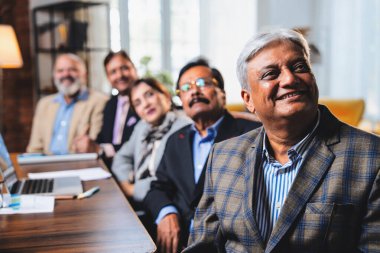 Hintli beş iş adamı sunum ve alkışları Hintli üst düzey Asyalı iş adamlarına yakın plan olarak görüyor ve modern ofis içinde masada otururken veya ayakta dururken başarılı brifing veriyorlar.