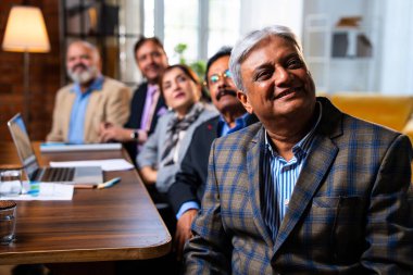 Hintli beş iş adamı sunum ve alkışları Hintli üst düzey Asyalı iş adamlarına yakın plan olarak görüyor ve modern ofis içinde masada otururken veya ayakta dururken başarılı brifing veriyorlar.