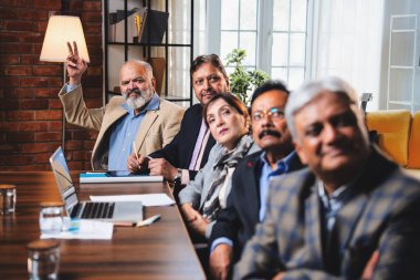 Hintli beş iş adamı sunum ve alkışları Hintli üst düzey Asyalı iş adamlarına yakın plan olarak görüyor ve modern ofis içinde masada otururken veya ayakta dururken başarılı brifing veriyorlar.