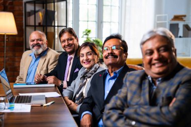 Hintli beş iş adamı sunum ve alkışları Hintli üst düzey Asyalı iş adamlarına yakın plan olarak görüyor ve modern ofis içinde masada otururken veya ayakta dururken başarılı brifing veriyorlar.