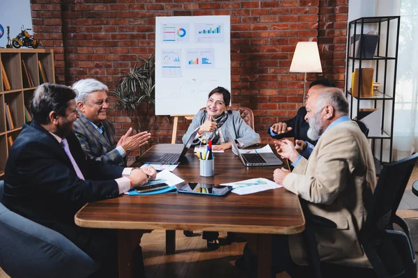 Hintli üst düzey iş adamları, Hindistan 'da üst düzey Asyalı iş adamları olarak birlikte çalışarak, rahat, modern kurumsal işyerlerindeki görevleri incelerken dizüstü bilgisayarları ve masa başındaki kağıtları kullanarak iş birliği yapıyorlar.