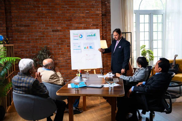 Hintli işadamları, Hindistan 'ın Asya iş dünyasının üst düzey yöneticileri olarak, şirket büyümesini ve finansal projeksiyon stratejisini modern ofiste incelerken, grafikte tartışıyorlar.