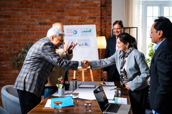 Hintli iş adamları anlaşmadan sonra el sıkışıyor. Hintli kıdemli Asyalı işadamı modern ofis toplantılarında gülümserken başarılı bir anlaşmayı imzalıyor.