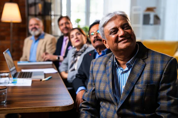 Hintli beş iş adamı sunum ve alkışları Hintli üst düzey Asyalı iş adamlarına yakın plan olarak görüyor ve modern ofis içinde masada otururken veya ayakta dururken başarılı brifing veriyorlar.