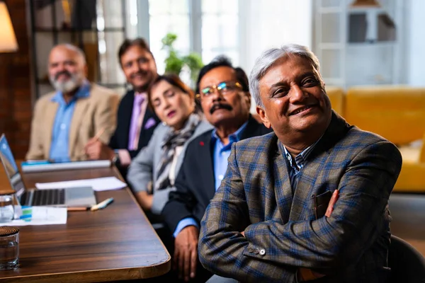 Hintli beş iş adamı sunum ve alkışları Hintli üst düzey Asyalı iş adamlarına yakın plan olarak görüyor ve modern ofis içinde masada otururken veya ayakta dururken başarılı brifing veriyorlar.