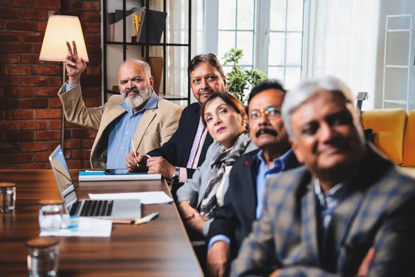 Hintli beş iş adamı sunum ve alkışları Hintli üst düzey Asyalı iş adamlarına yakın plan olarak görüyor ve modern ofis içinde masada otururken veya ayakta dururken başarılı brifing veriyorlar.