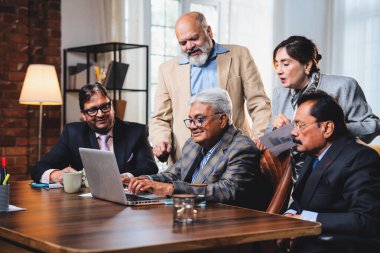 Hintli üst düzey iş adamları, Hindistan 'da üst düzey Asyalı iş adamları olarak birlikte çalışarak, rahat, modern kurumsal işyerlerindeki görevleri incelerken dizüstü bilgisayarları ve masa başındaki kağıtları kullanarak iş birliği yapıyorlar.