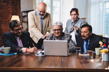 Hintli üst düzey iş adamları, Hindistan 'da üst düzey Asyalı iş adamları olarak birlikte çalışarak, rahat, modern kurumsal işyerlerindeki görevleri incelerken dizüstü bilgisayarları ve masa başındaki kağıtları kullanarak iş birliği yapıyorlar.