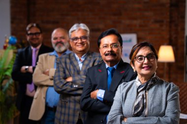 Hintli üst düzey iş adamlarının portresi gülümseyerek alkışlarken, Hintli üst düzey Asyalı yöneticiler modern şirket işyerindeki kameralara bakarak başarıyı alkışlıyor ve kutluyorlar.