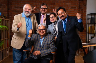 Hintli üst düzey iş adamlarının portresi Hintli üst düzey Asya yöneticileri kılığına girmiş patronun kanat koltuğunda otururken modern şirket ofisinde poz verirken kameraya gülümsüyor.