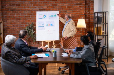 Hintli işadamları, Hindistan 'ın Asya iş dünyasının üst düzey yöneticileri olarak, şirket büyümesini ve finansal projeksiyon stratejisini modern ofiste incelerken, grafikte tartışıyorlar.