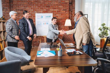 Hintli işadamları, Hindistan 'ın üst düzey Asyalı iş adamları olarak sunum yaparken el sıkışıyorlar. Yüksek yönetim, samimi modern ofis grafiği kullanarak başarılı büyüme projeksiyonunu kutluyor.