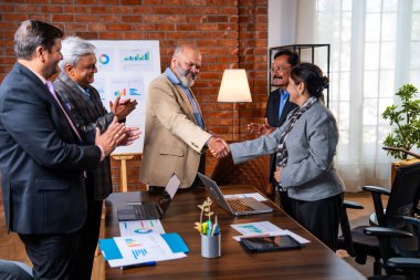 Hintli işadamları, Hindistan 'ın üst düzey Asyalı iş adamları olarak sunum yaparken el sıkışıyorlar. Yüksek yönetim, samimi modern ofis grafiği kullanarak başarılı büyüme projeksiyonunu kutluyor.