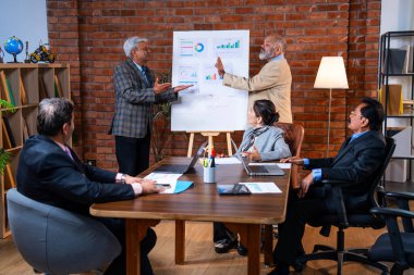 Hintli üst düzey iş adamları modern ofiste tartışırken Hintli üst düzey Asyalı iş adamları şirket büyümesi, strateji ve dizüstü bilgisayarla çalışırken masadaki kağıtlar hakkında hararetli tartışmalara girişiyorlar.