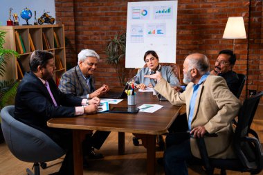 Hintli üst düzey iş adamları, Hindistan 'da üst düzey Asyalı iş adamları olarak birlikte çalışarak, rahat, modern kurumsal işyerlerindeki görevleri incelerken dizüstü bilgisayarları ve masa başındaki kağıtları kullanarak iş birliği yapıyorlar.