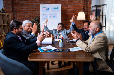Hintli iş adamları, Hintli üst düzey Asyalı yöneticilerin modern ofis işyerindeki şirket toplantılarında elde ettikleri başarıları alkışlayarak ve beşlik çakarak kutluyorlar.