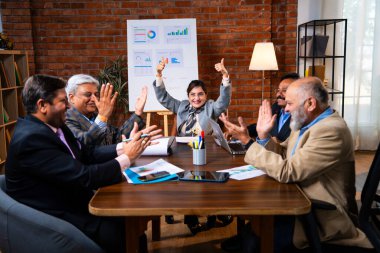 Hintli iş adamları, Hintli üst düzey Asyalı yöneticilerin modern ofis işyerindeki şirket toplantılarında elde ettikleri başarıları alkışlayarak ve beşlik çakarak kutluyorlar.