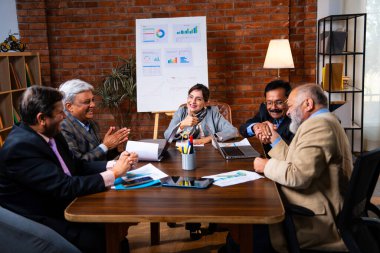 Hintli üst düzey iş adamları, Hindistan 'da üst düzey Asyalı iş adamları olarak birlikte çalışarak, rahat, modern kurumsal işyerlerindeki görevleri incelerken dizüstü bilgisayarları ve masa başındaki kağıtları kullanarak iş birliği yapıyorlar.