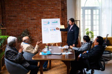 Hintli işadamları, Hindistan 'ın Asya iş dünyasının üst düzey yöneticileri olarak, şirket büyümesini ve finansal projeksiyon stratejisini modern ofiste incelerken, grafikte tartışıyorlar.