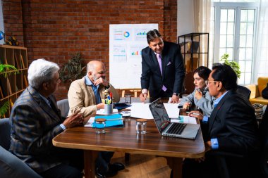 Hintli işadamları, Hindistan 'da rahat modern ofis masasında çalışırken, üst düzey Asyalı iş adamları ve üst düzey yönetim stratejisi olarak plan üzerinde tartışıyorlar.