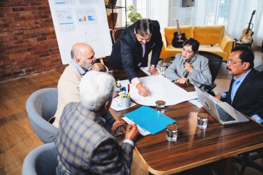Hintli işadamları, Hindistan 'da rahat modern ofis masasında çalışırken, üst düzey Asyalı iş adamları ve üst düzey yönetim stratejisi olarak plan üzerinde tartışıyorlar.