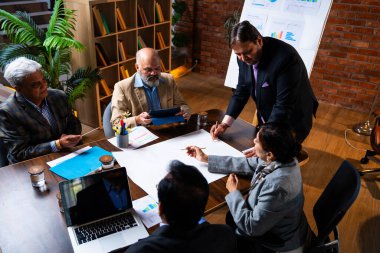 Hintli işadamları, Hindistan 'da rahat modern ofis masasında çalışırken, üst düzey Asyalı iş adamları ve üst düzey yönetim stratejisi olarak plan üzerinde tartışıyorlar.