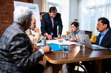 Hintli işadamları, Hindistan 'da rahat modern ofis masasında çalışırken, üst düzey Asyalı iş adamları ve üst düzey yönetim stratejisi olarak plan üzerinde tartışıyorlar.