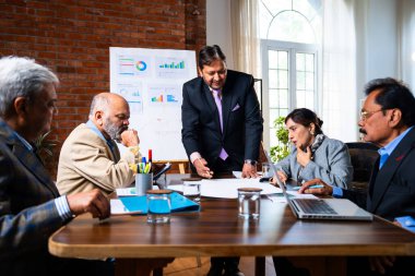 Hintli işadamları, Hindistan 'da rahat modern ofis masasında çalışırken, üst düzey Asyalı iş adamları ve üst düzey yönetim stratejisi olarak plan üzerinde tartışıyorlar.