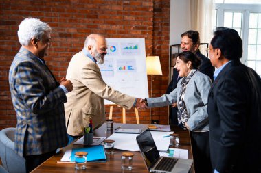 Hintli iş adamları anlaşmadan sonra el sıkışıyor. Hintli kıdemli Asyalı işadamı modern ofis toplantılarında gülümserken başarılı bir anlaşmayı imzalıyor.