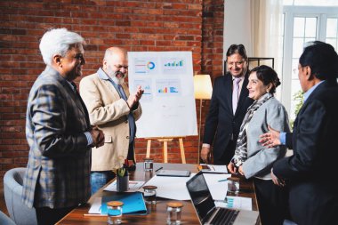 Hintli iş adamları anlaşmadan sonra el sıkışıyor. Hintli kıdemli Asyalı işadamı modern ofis toplantılarında gülümserken başarılı bir anlaşmayı imzalıyor.