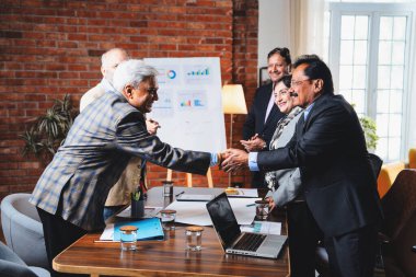 Hintli iş adamları anlaşmadan sonra el sıkışıyor. Hintli kıdemli Asyalı işadamı modern ofis toplantılarında gülümserken başarılı bir anlaşmayı imzalıyor.