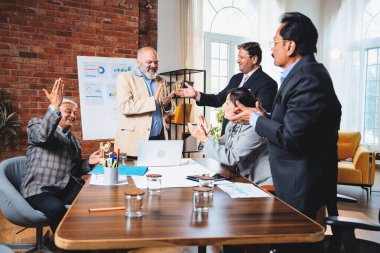 Hintli iş adamları anlaşmadan sonra el sıkışıyor. Hintli kıdemli Asyalı işadamı modern ofis toplantılarında gülümserken başarılı bir anlaşmayı imzalıyor.