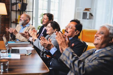 Hintli beş iş adamı sunum ve alkışları Hintli üst düzey Asyalı iş adamlarına yakın plan olarak görüyor ve modern ofis içinde masada otururken veya ayakta dururken başarılı brifing veriyorlar.