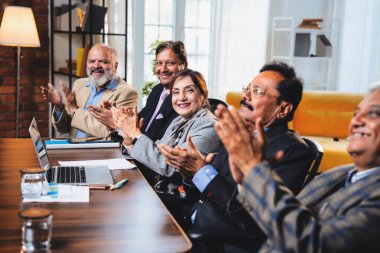 Hintli beş iş adamı sunum ve alkışları Hintli üst düzey Asyalı iş adamlarına yakın plan olarak görüyor ve modern ofis içinde masada otururken veya ayakta dururken başarılı brifing veriyorlar.
