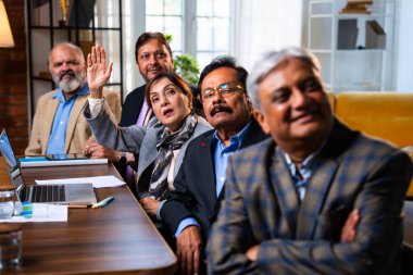 Hintli beş iş adamı sunum ve alkışları Hintli üst düzey Asyalı iş adamlarına yakın plan olarak görüyor ve modern ofis içinde masada otururken veya ayakta dururken başarılı brifing veriyorlar.