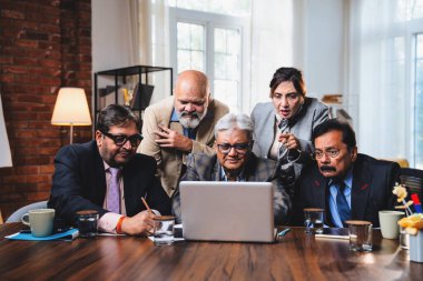 Hintli üst düzey iş adamları, Hindistan 'da üst düzey Asyalı iş adamları olarak birlikte çalışarak, rahat, modern kurumsal işyerlerindeki görevleri incelerken dizüstü bilgisayarları ve masa başındaki kağıtları kullanarak iş birliği yapıyorlar.