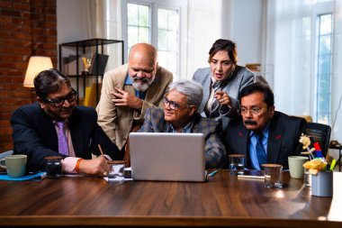 Hintli üst düzey iş adamları, Hindistan 'da üst düzey Asyalı iş adamları olarak birlikte çalışarak, rahat, modern kurumsal işyerlerindeki görevleri incelerken dizüstü bilgisayarları ve masa başındaki kağıtları kullanarak iş birliği yapıyorlar.