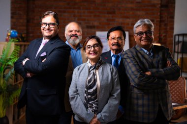 Hintli üst düzey iş adamlarının portresi gülümseyerek alkışlarken, Hintli üst düzey Asyalı yöneticiler modern şirket işyerindeki kameralara bakarak başarıyı alkışlıyor ve kutluyorlar.