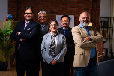 Hintli üst düzey iş adamlarının portresi gülümseyerek alkışlarken, Hintli üst düzey Asyalı yöneticiler modern şirket işyerindeki kameralara bakarak başarıyı alkışlıyor ve kutluyorlar.